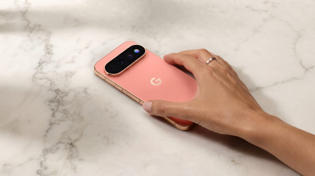 Hand resting on the coral-colored Google Pixel 11 Pro smartphone placed on a white marble countertop